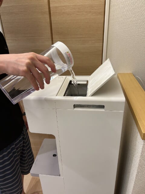 ウォータースタンド「ピュアライフ」のユーザー・青木さん(仮名・37歳女性)の利用画像。給水タンクに水を注いでいる様子